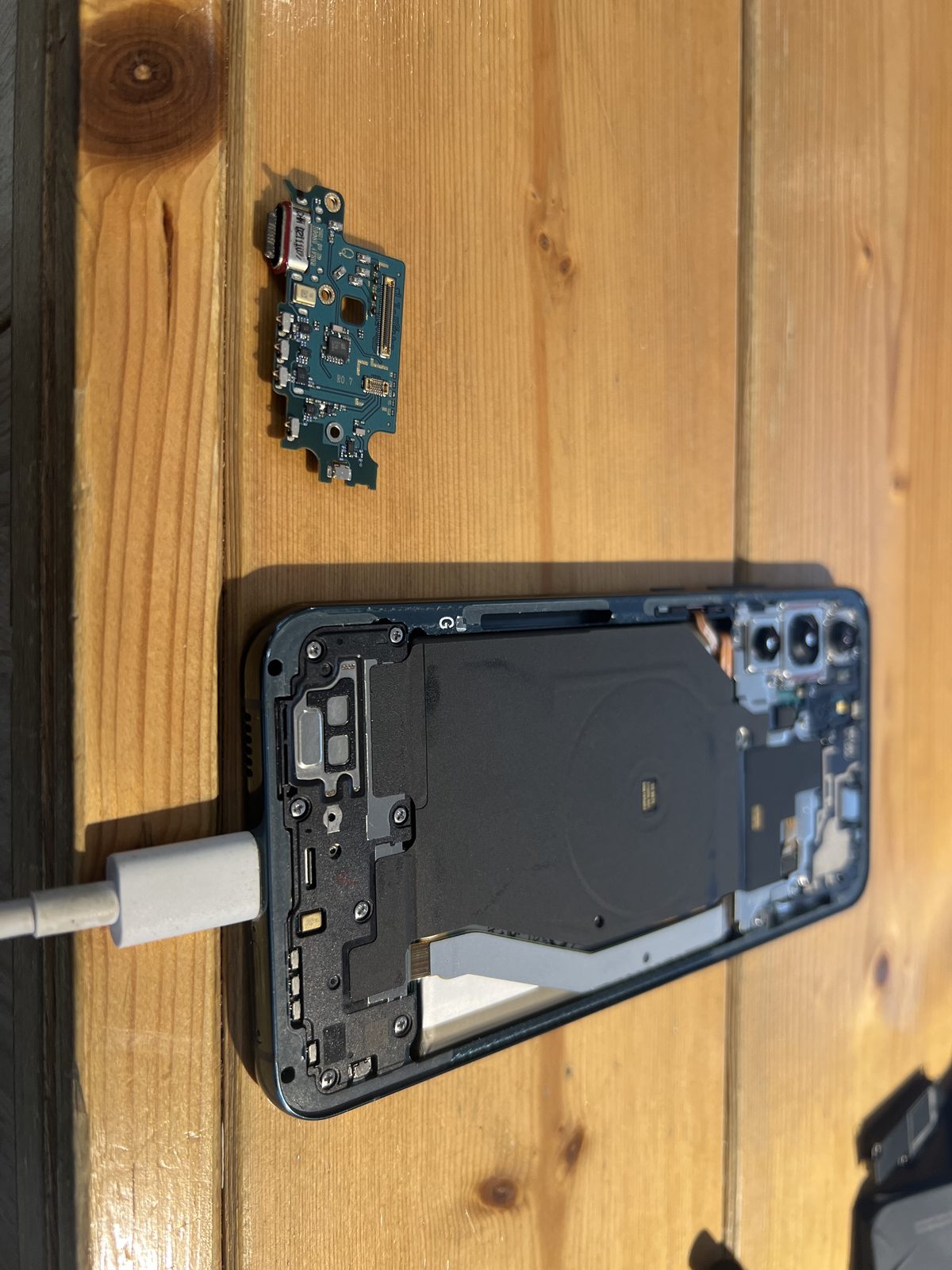 Galaxy S22 Ultra 拆下的充電埠小板與拆解中的機身內部