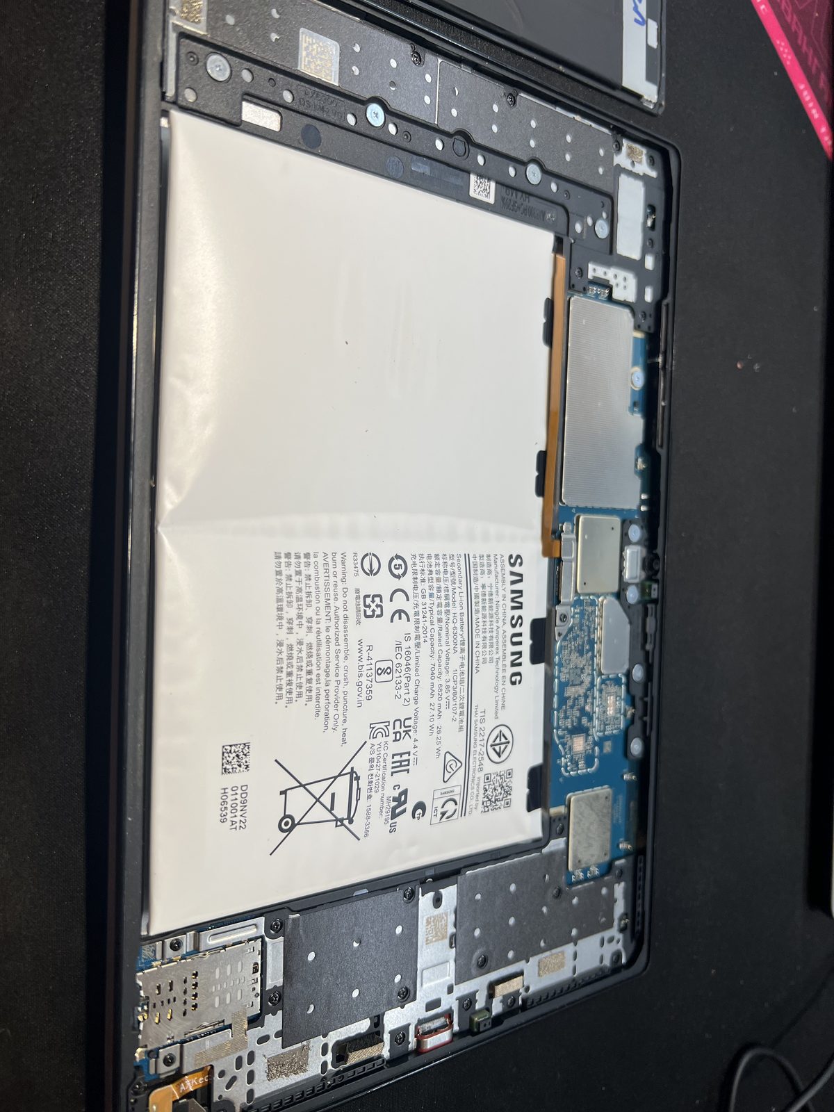 三星 Galaxy Tab A8 平板拆機後，可見膨脹變形的 Samsung HQ-6500NA 電池與主機板